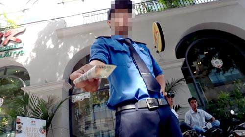 
Nhân viên bãi giữ xe máy trước số nhà 82 Nguyễn Du, quận 1 thu tiền người đi ô tô - Ảnh: Cắt clip điều tra.
