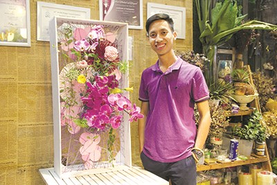 Nguyễn Phi Minh bên cạnh một tác phẩm hoa nghệ thuật vừa hoàn thành. Ảnh: H.L