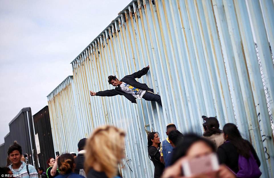 Người di cư trèo lên hàng rào biên giới Mỹ - Mexico - Ảnh 2.