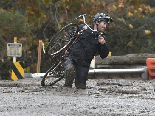 
Một người đàn ông vác xe đạp trên một con đường ngập bùn ở khu vực Carpinteria. Ảnh: AP
