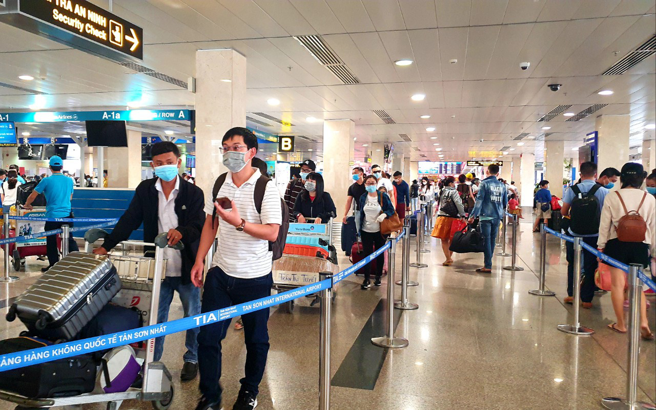 Sân bay Tân Sơn Nhất đông nghẹt ngày 25 Tết, nhiều khách trùm kín người để phòng dịch - Ảnh 2.
