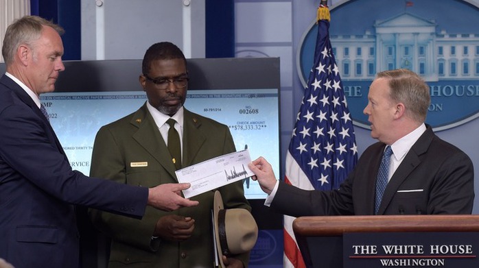 Phát ngôn viên Nhà Trắng Sean Spicer (phải) hôm 3-4 trao tấm séc trị giá 78.333 USD cho Bộ trưởng Bộ Nội vụ Ryan Zinke. Ảnh: AP