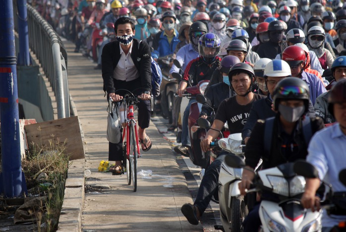 Một nam thanh niên không còn kiên nhẫn chờ đợi trong đám kẹt xe, vác xe đạp lên vỉa hành lang cầu để chạy