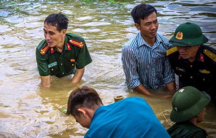 Công an, bộ đội dầm  mình trong nước ăn vội, giúp dân chống lũ dữ - Ảnh 1.