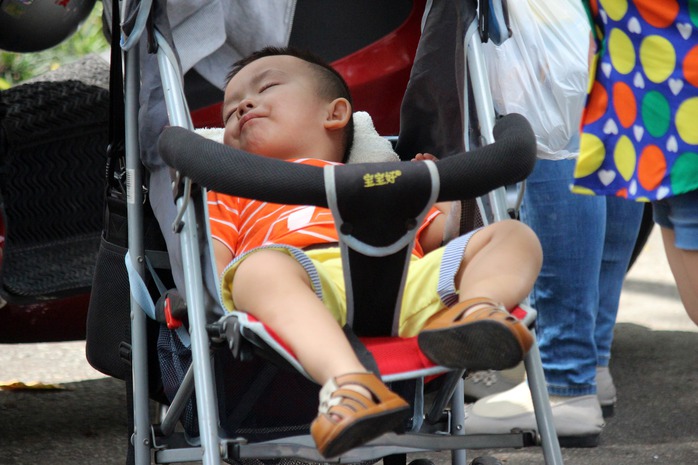 
Quá mệt mỏi, em bé nằm ngủ say sưa trên xe đẩy.
