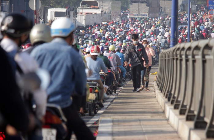 Một nam thanh niên không còn kiên nhẫn chờ đợi trong đám kẹt xe, vác xe đạp lên vỉa hành lang cầu để chạy