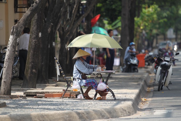 
Người phụ nữ bán vé số dù ngồi dưới tán cây nhưng vẫn che thêm dù để tránh nắng. Cô cho biết những người làm nghề như cô dù trời nắng nóng cỡ nào cũng phải ra đường buôn bán, nếu ở nhà sẽ không có tiền trang trải. Những ngày qua, cứ về đến nhà là người cô như cọng bún thiu.
