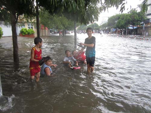 Trẻ em vô tư vui đùa trong dòng nước đen.