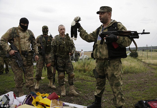 Belongings: A pro-Russian fighter holds up a teddy bear near the crash site 