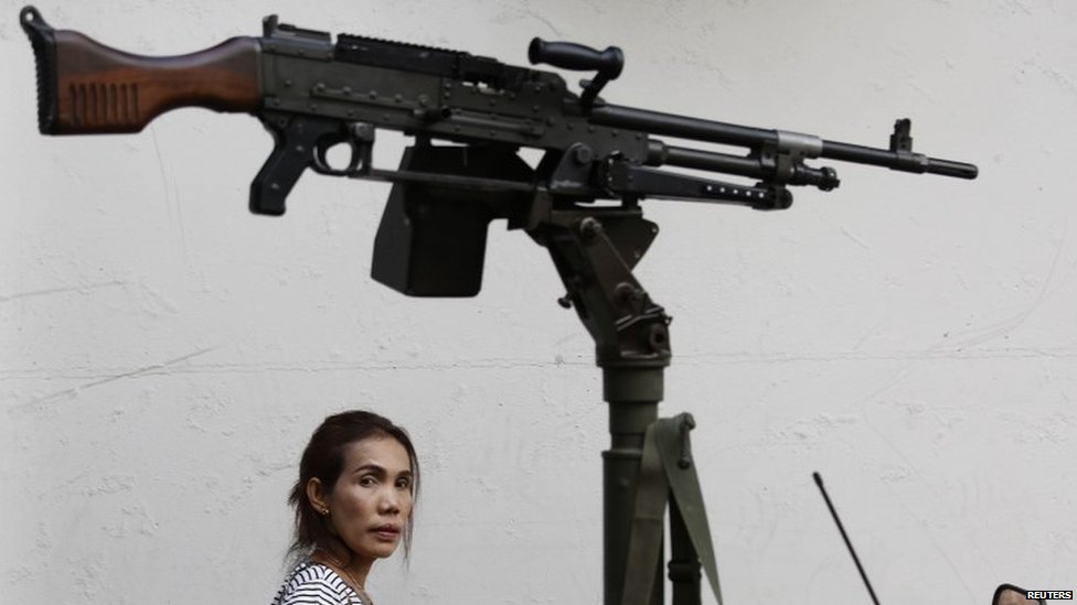 A morning commuter passes behind a machine gun mounted on a military vehicle (20 May 2014)