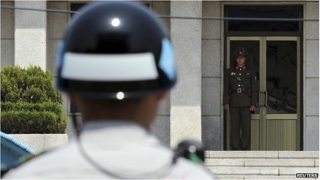 A North Korean soldier (R) looks south on the North side, as a South Korean soldier stands guard at the truce village of Panmunjom in the demilitarized zone which separates the two Koreas, May 14