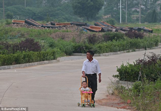 A father pushes his baby down a road past a pile of coffins smashed by officials to drive home the looming ban on burials brought in because cemeteries are taking up too much space in Anhui province, China