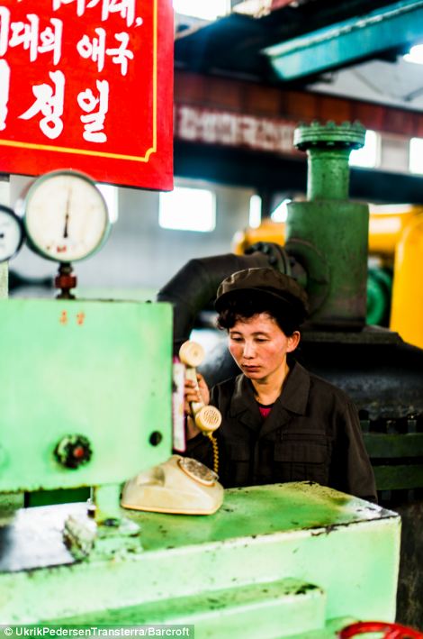 Hardly working? A woman in Hamhungs fertiliser factory answers a very old-fashioned telephone