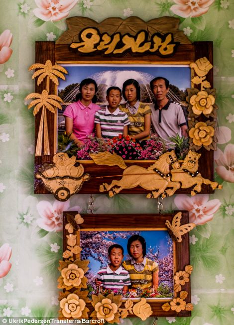 A North Korean family are pictured together in this set of family photographs hanging on a wall in Chilbo, North Korea