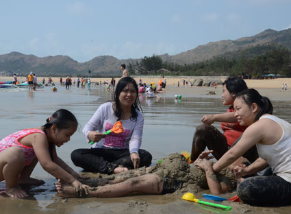 Du khách chơi trò đắp cát tại bãi tắm thuộc KDL Thùy Dương. 
