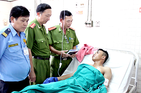 Đại diện Công an TP.Biên Hòa thăm hỏi anh Phạm Minh Dương đang nằm điều trị tại Bệnh viện Chợ Rẫy. Ảnh: T. Danh