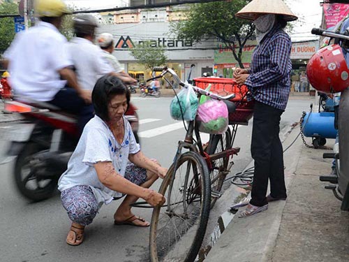 Sau khi bị tạt axít, mất việc làm, chị Vũ Thị Loan cùng gia đình vá xe ở lề đường để kiếm sống qua ngày Ảnh: BẢO NGỌC