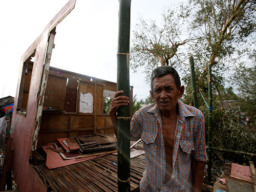 Một người dân đứng trước ngôi nhà bị bão Rammasun tàn phá ở thành phố Batangas - Philippines hôm 17-7  Ảnh: REUTERS