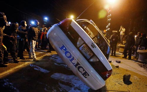 Người biểu tình ở Ferguson lật xe cảnh sát đêm 25-11 
Ảnh: REUTERS