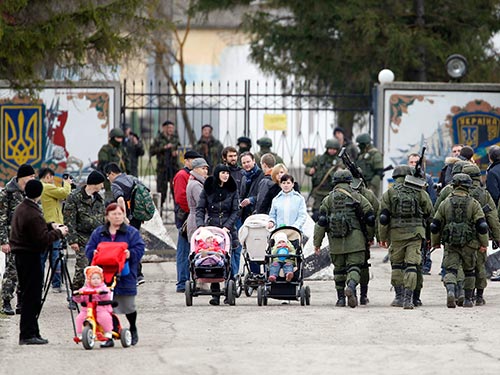 Người dân địa phương trao đổi với các binh lính nghi là của Nga bên ngoài đơn vị quân đội Ukraine ở làng Perevalnoye, Crimea ngày 5-3 Ảnh: REUTERS