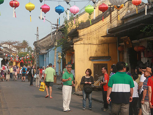 Hướng dẫn viên người Trung Quốc (đeo kính đen) dẫn đoàn tham quan tại TP Hội An Ảnh: TRẦN THƯỜNG