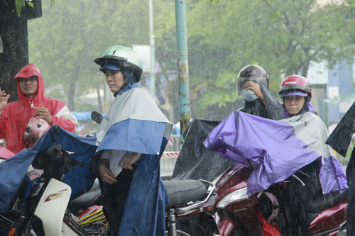 Trước cổng điểm thi hết chỗ để trú mưa nên không ít phụ huynh phải ngồi chờ trên xe máy dựng bên đường giữa trời mưa.
