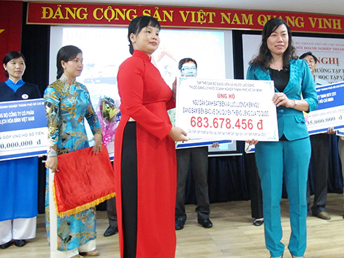 Bà Lê Thị Hồng Hậu, Bí thư Đảng ủy Khối Doanh nghiệp TP HCM (trái), trao biểu trưng cho đại diện Ủy ban MTTQ TP  Ảnh: HỒNG NHUNG