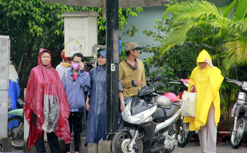 Nhiều phụ huynh đội mưa đứng chờ con tại hội đồng thi Trường THPT Võ Thị Sáu (quận Bình Thạnh)