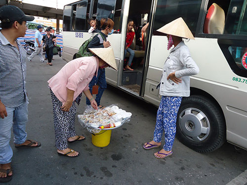 Hàng rong ở Bến xe Miền Tây đến từng xe mời mọc khách Ảnh: Nguyễn Phượng