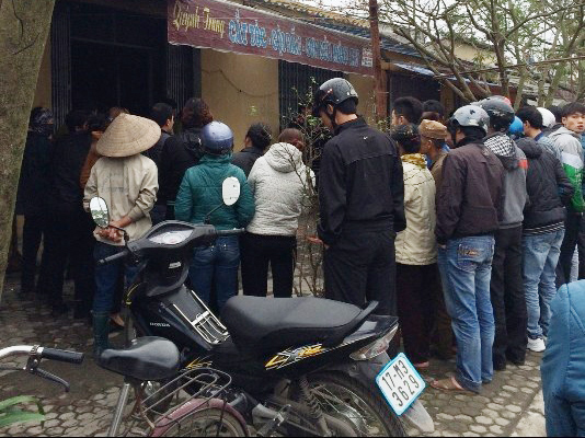 Người hiếu kỳ đứng bên ngoài trong khi công an tiến hành khám nghiệm hiện trường