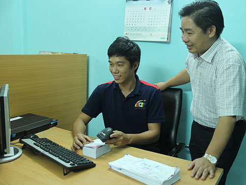 Anh Lương Quốc Huy (đứng) hướng dẫn nhân viên thực hiện quét mã vạch lấy thông tin khách hàng