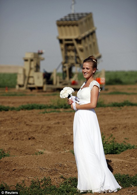 Israeli bride Rinat Shiklar, 22, from Kibbutz Alumim near the Gaza Strip, poses for a wedding photo in front of an Iron Dome rocket launcher near the southern town of Netivot June 21, 2012