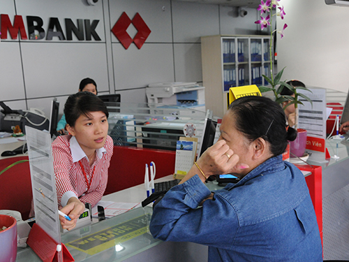 Khách hàng tìm hiểu lãi suất mới tại một ngân hàng ở TP HCM Ảnh: HỒNG THÚY