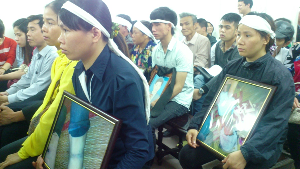 Người nhà nạn nhân Nguyễn Mậu Thuận mang theo di ảnh và ảnh chụp những vết thương của nạn nhân tại phiên toà