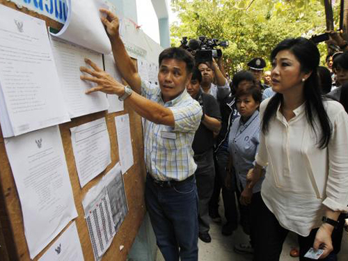 Thủ tướng Thái Lan Yingluck Shinawatra (phải) kiểm tra danh sách cử tri trước khi bỏ phiếu tại Bangkok ngày 30-3Ảnh: REUTERS