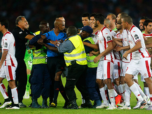 Lực lượng an ninh bảo vệ trọng tài Rajindraprasd trước sự truy đuổi của các cầu thủ Tunisia Ảnh: REUTERS
