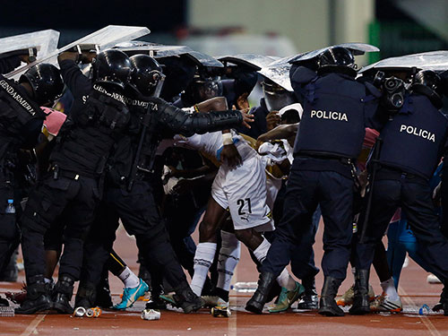 Cảnh sát che chắn cho cầu thủ Ghana trước “mưa” chai lọ của CĐV Guinea Xích Đạo  Ảnh: REUTERS