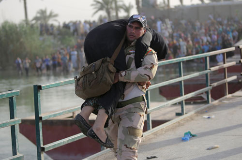 Binh sĩ Iraq giúp một phụ nữ bỏ chạy khỏi TP Ramadi qua cây cầu ở ngoại ô thủ đô Baghdad Ảnh: REUTERS