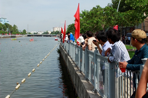 Người dân hai bờ kênh theo dõi vào dùng điện thoại ghi lại cảnh đua thuyền