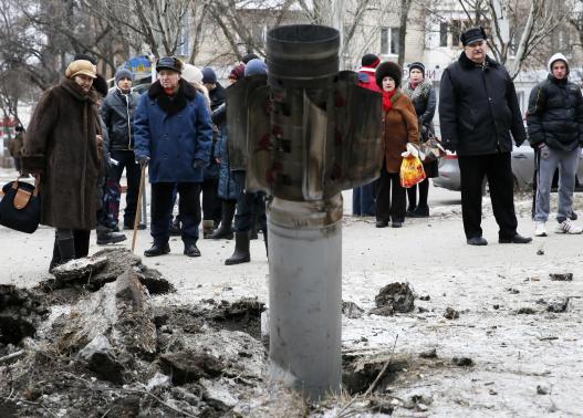 Người dân đứng gần quả rocket ở thị trấn Kramatorsk, miền Đông Ukraine hôm 10-2. Ảnh: Reuters