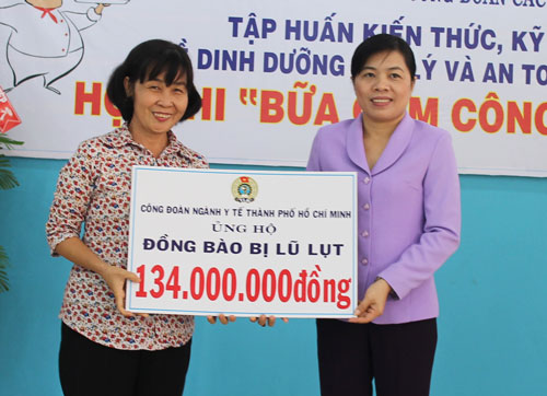 Bà Lê Thị Mỹ Châu, Chủ tịch Công đoàn ngành Y tế TP HCM (trái), trao tiền hỗ trợ cho đại diện LĐLĐ TP HCM