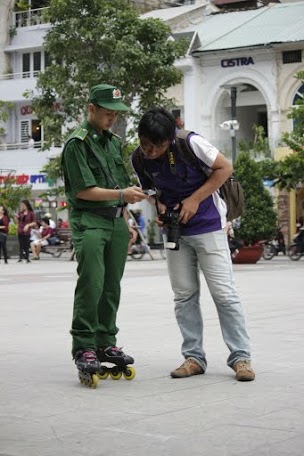 Một chiến sĩ TNXP đang chia sẻ thông tin về đội TNXP trượt patin một người dân trên phố đi bộ.