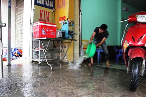 Mưa cộng triều cường đã đẩy nhiều nhà dân vào thế… tát nước chống ngập Ảnh: GIA MINH