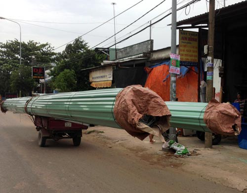 Chiếc xe ba gác chở cuộn tôn dài hơn chục mét nghênh ngang lao trên đường Ảnh: GIA MINH