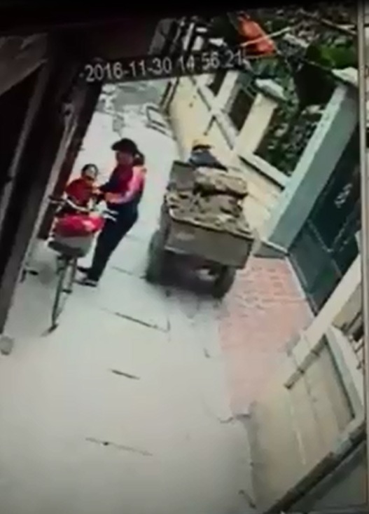 
Sau vụ tai nạn, người phụ nữ bế bé trai lên yên xe đạp. Ảnh cắt từ video
