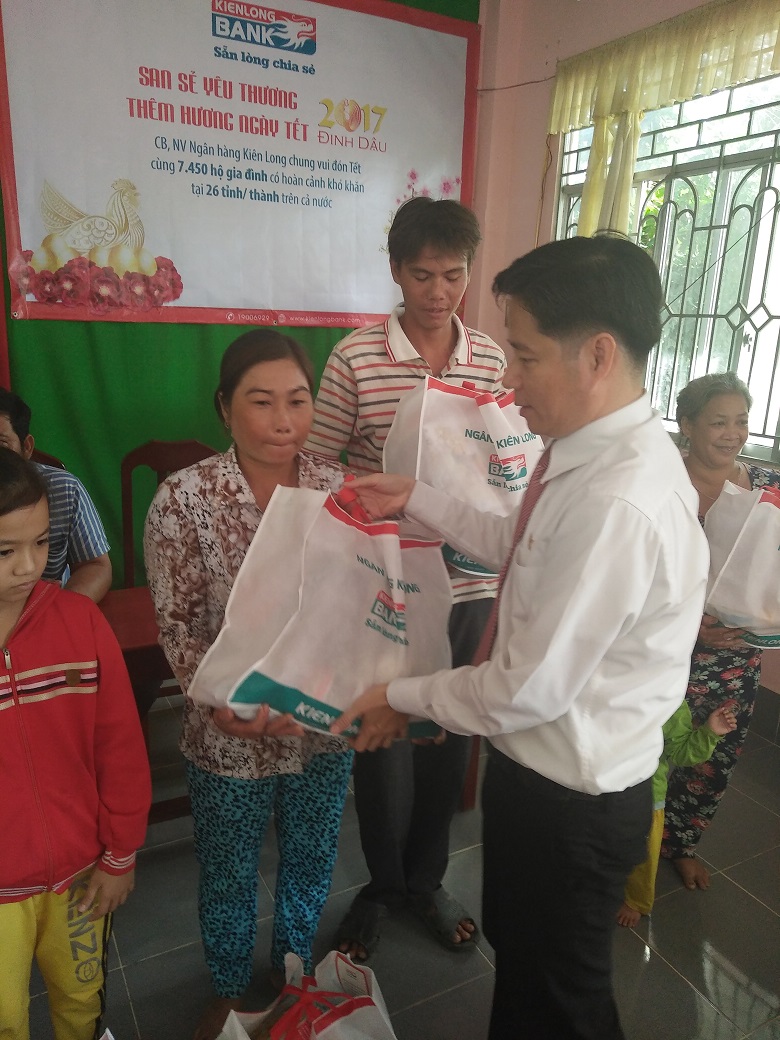 
Đại diện Kienlongbank (bên phải) tặng quà Tết cho bà con (Ảnh: Tấn Thành)

