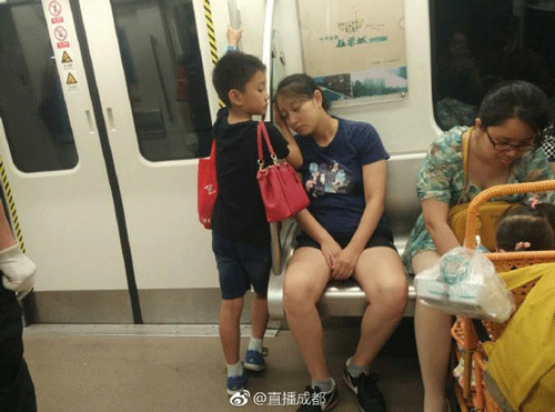 Cậu bé đứng kê tay cho mẹ ngủ ngon trên tàu điện ngầm - Ảnh 1.