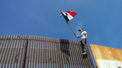 Người biểu tình Mỹ vẫy cờ Mexico tại hàng rào biên giới ngăn cách giữa Mexico và Mỹ ở Tijuana Ảnh: EPA