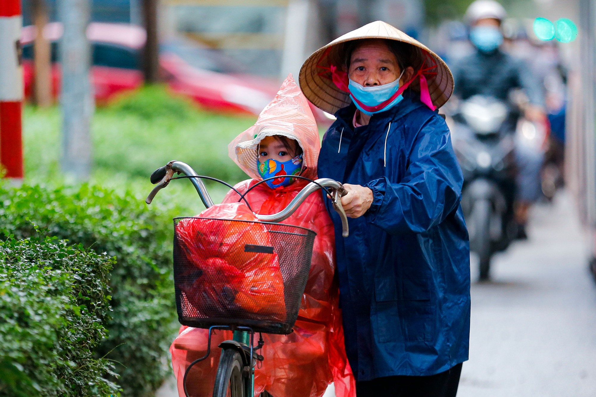 Người dân Hà Nội trùm áo mưa đón không khí lạnh - Ảnh 6.