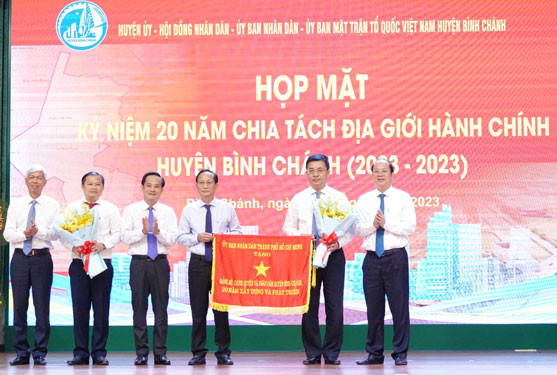 Phó Bí thư Thành ủy TP HCM Nguyễn Hồ Hải (bìa phải) và Phó Chủ tịch UBND TP HCM Võ Văn Hoan (bìa trái) trao cờ truyền thống đến Đảng bộ, chính quyền và nhân dân huyện Bình Chánh